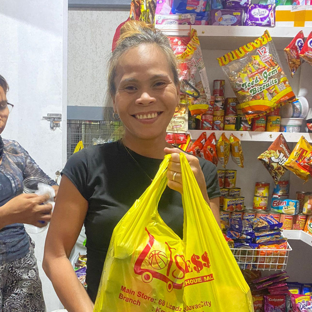 A yufin user holding up a plastic bag filled with her orders, fulfilled by yufin's brand partner, Lots for Less.