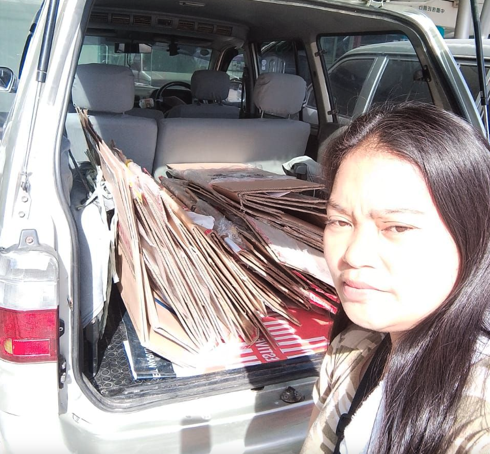 A yufin user standing at the back of a vehicle with flattened boxes inside.