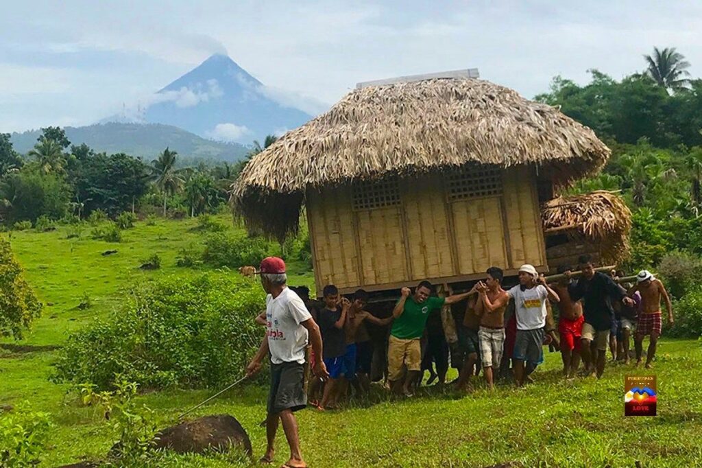 A group of people carrying a bahay kubo to relocate it.