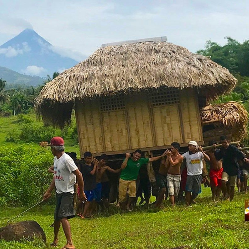 A group of people carrying a bahay kubo to relocate it.