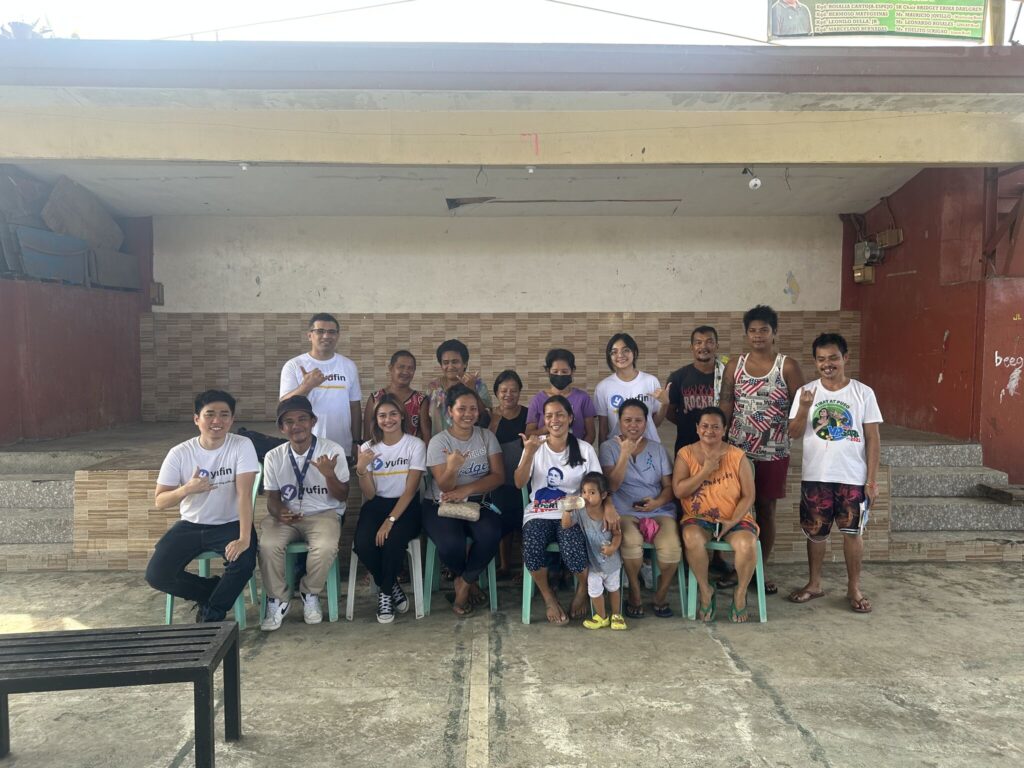 The yufin team with a group of people forming the yufin symbol with their hands.