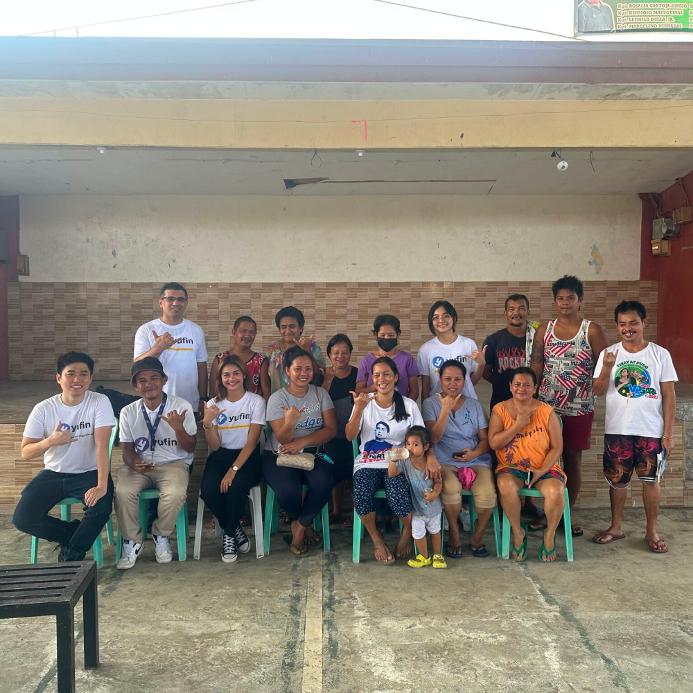 The yufin team with a group of people forming the yufin symbol with their hands.