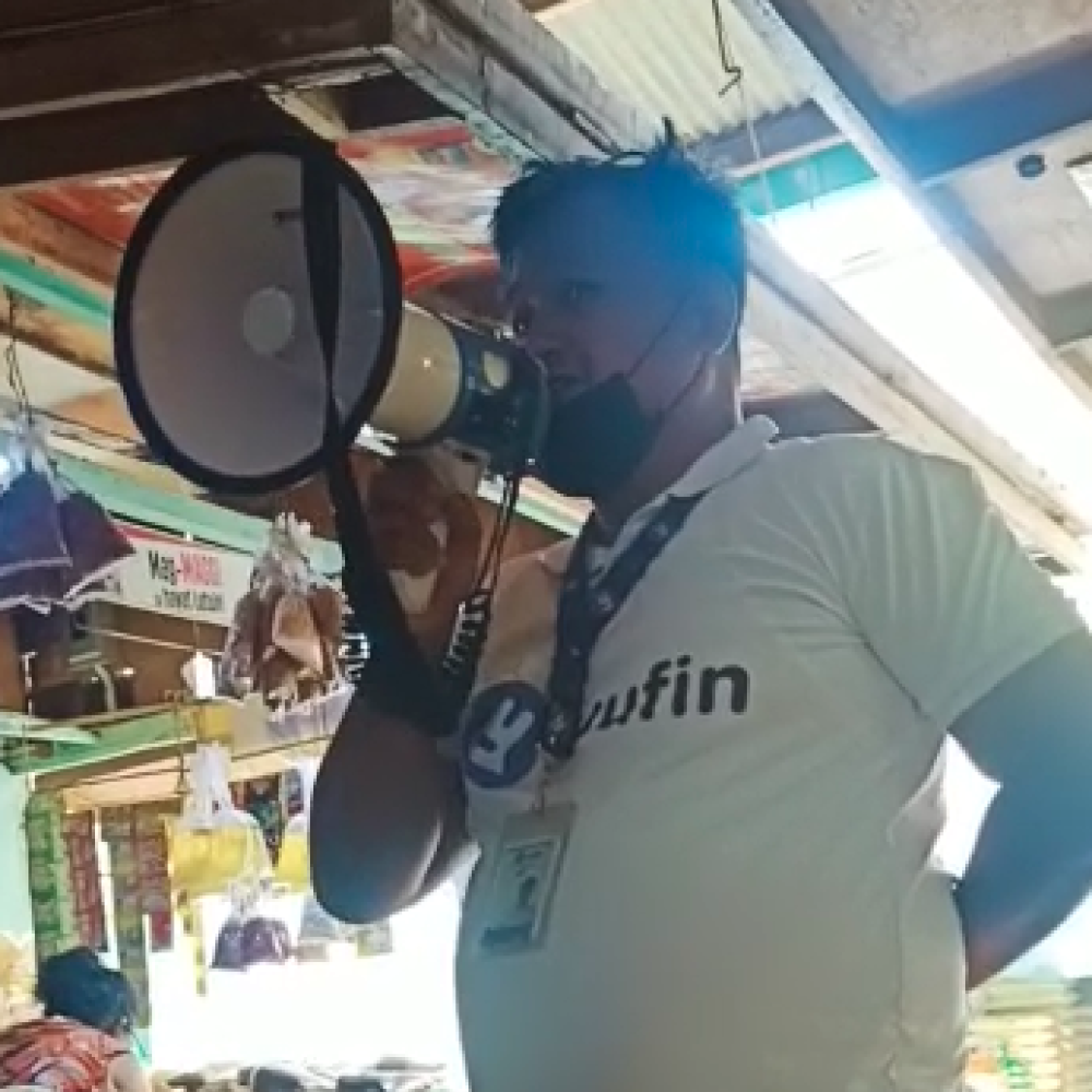 A screenshot from a video of a yufin field sales ambassador using a megaphone to speak to yufin users.