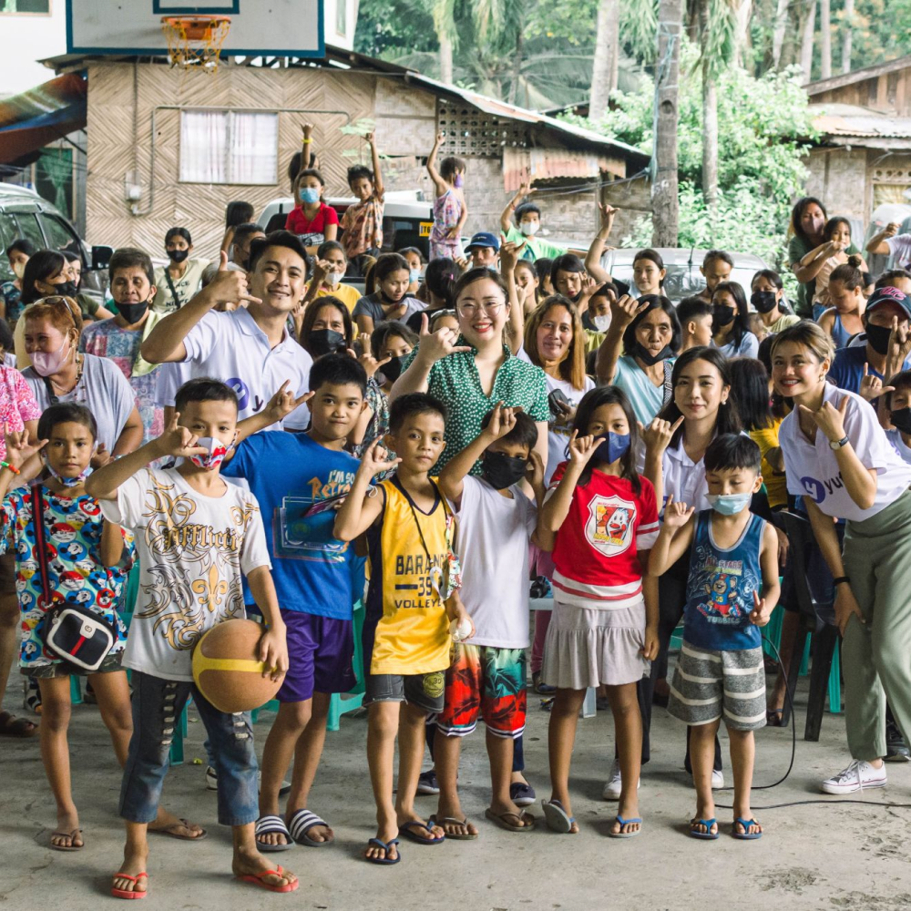 The yufin team with a group of people making the yufin symbol with their hands.