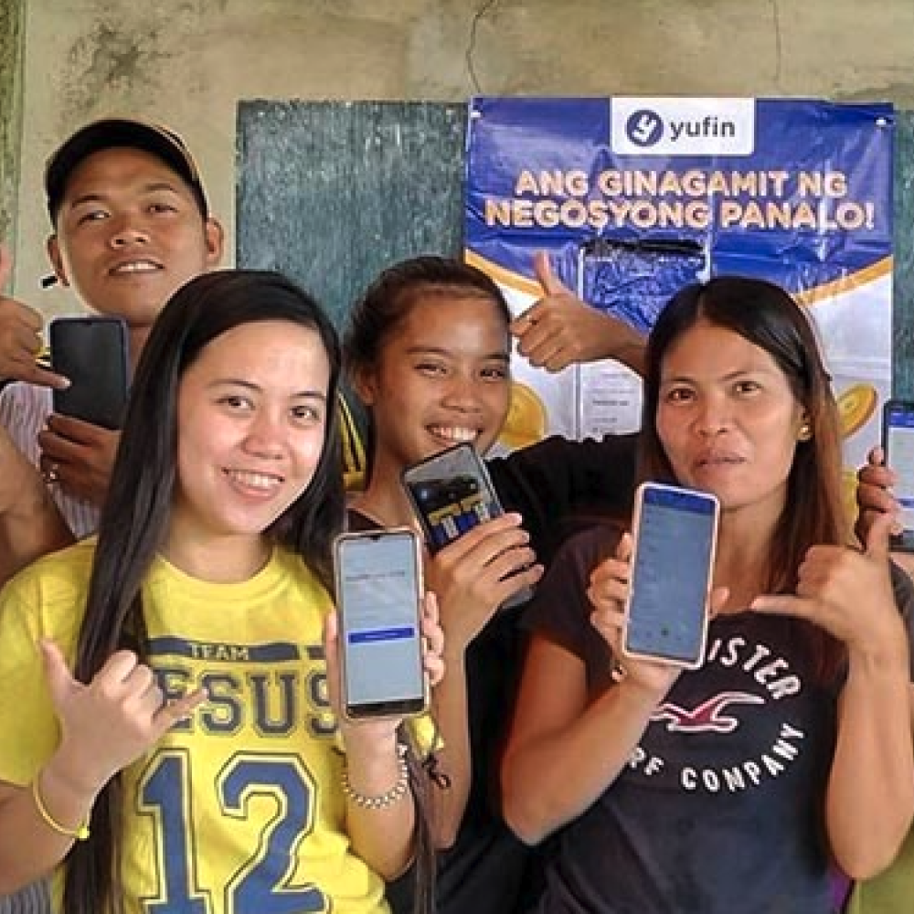 yufin merchants showing the yufin app on their smartphones.