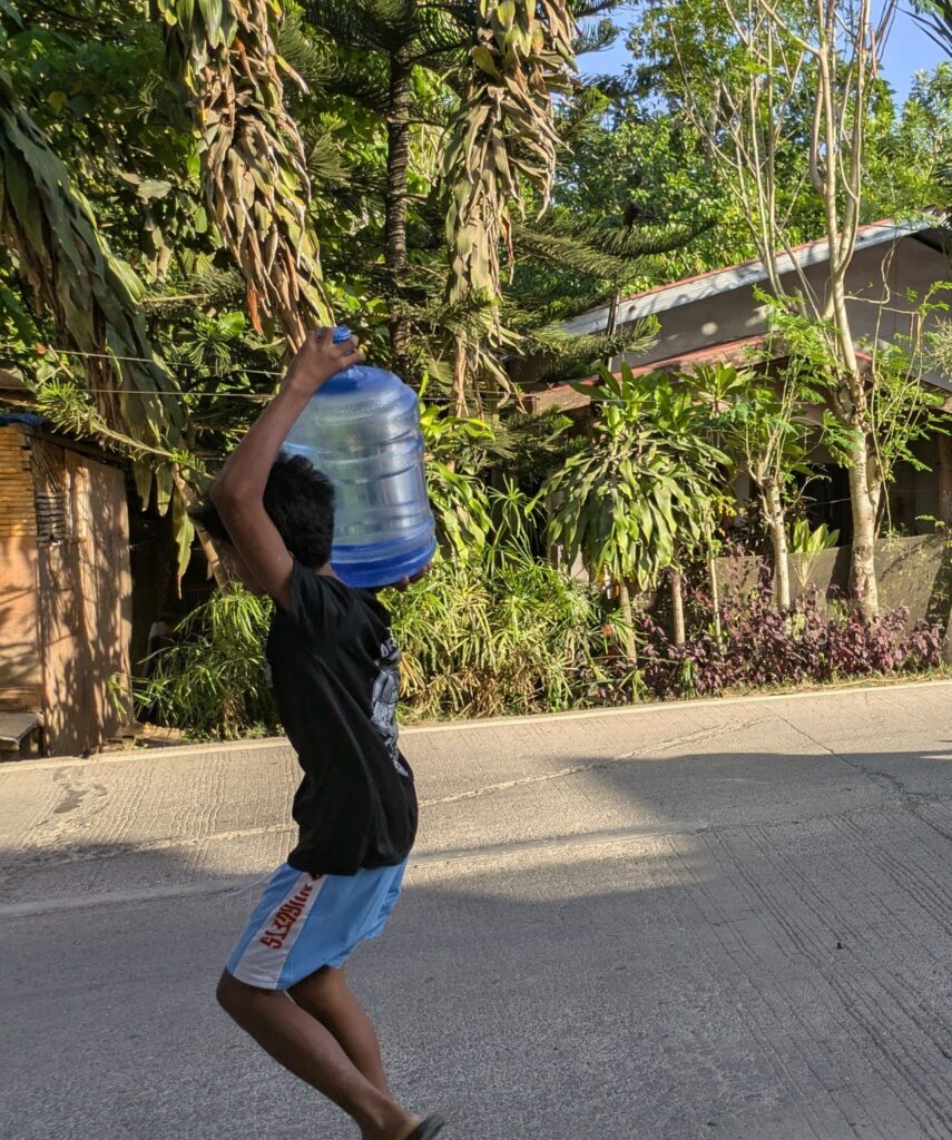 A child carrying a 5-gallon water dispenser bottle.